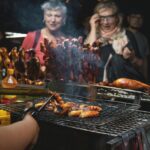 A food festival with people enjoying diverse cuisines, food trucks, and live music under string lights.