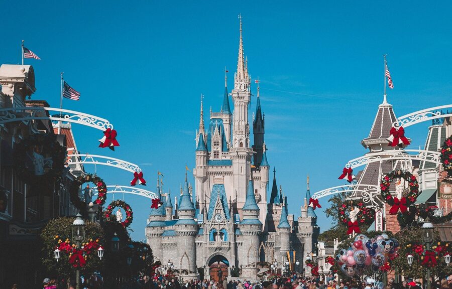 Cinderella Castle at Walt Disney World in Orlando, Florida, decorated for the holiday season with festive wreaths and red bows.