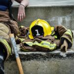 Firefighter resting on concrete steps with gear and helmet beside them