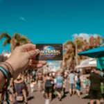 Hand holding a Universal Orlando Resort ticket with theme park crowd in background