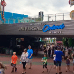 Entrance view of Universal Orlando Resort with tourists walking around the lively CityWalk area on a sunny day.