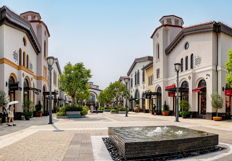 Outdoor Orlando outlet shopping mall with designer stores, trees, and a central fountain